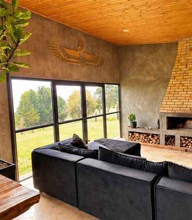 The living room with the golden scarab above tall windows and the brick fireplace
