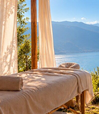 A massage table under white curtains, looking out over a lake and mountains