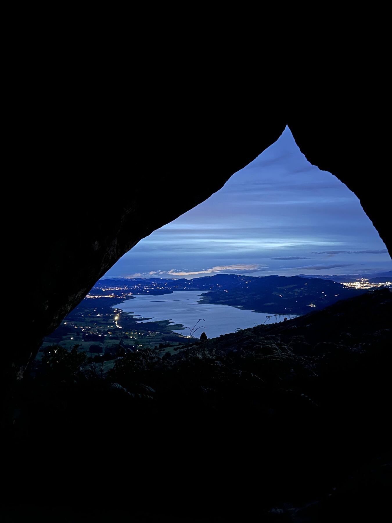 The cave at blue hour framing the valley lights and the lake