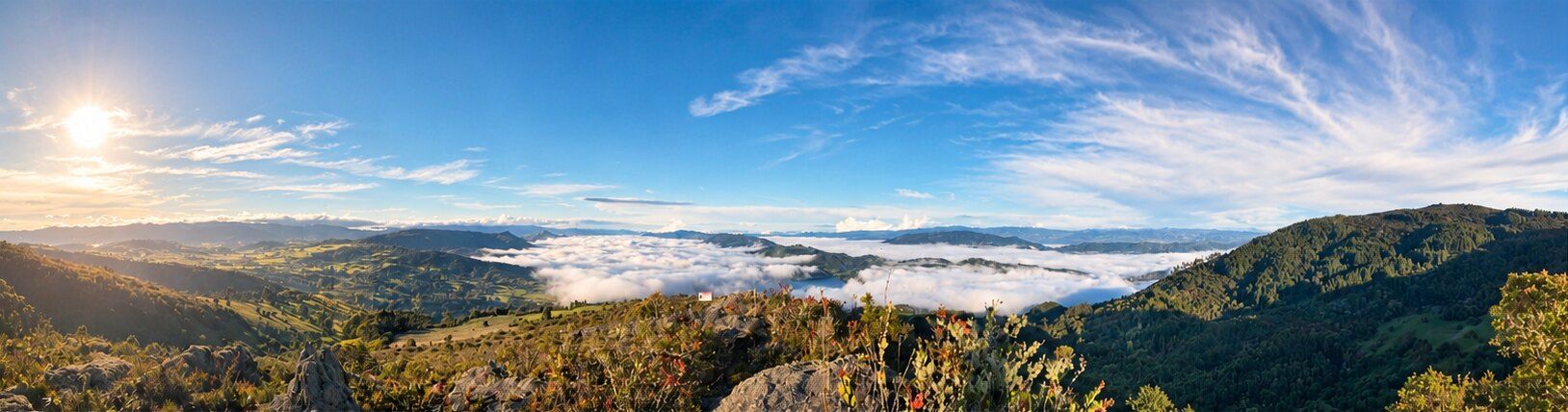 Panorama from the mountain: a sea of clouds in the valley, the lake beneath, and the sun in a deep blue sky